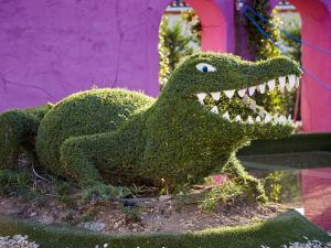 a green dinosaur statue in front of a pink building at Le Stelsia Resort in Saint-Sylvestre-sur-Lot