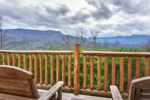 een houten terras met 2 stoelen en uitzicht op de bergen bij Pinnacle View Lodge by Stony Brook Cabins in Gatlinburg