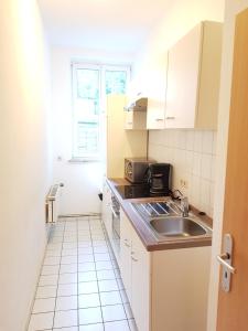 a small kitchen with white cabinets and a sink at City Apart Hannover in Hannover