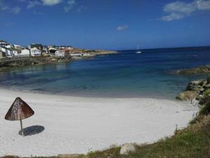 a beach with a cone shaped umbrella on the sand at Casa duples junto playa Cubelas in San Ciprián