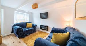 ein Wohnzimmer mit 2 blauen Sofas und einem TV in der Unterkunft Fowey, Cute Cottage in Fowey