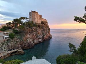 a castle on top of a cliff next to the ocean at Beach Apartment Francesko near Old Town in Dubrovnik