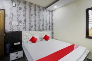 a bedroom with a white bed with red pillows at Hotel O One Plus Inn in Itwāri