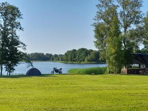 a person on a motorcycle next to a tent and a lake at Camping "Sīvezers" in Auleja