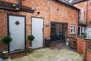 アシュボーンにあるStylish Home Peak District Ashbourne Alton towersの2つのドアと2つの植物があるレンガ造りの建物