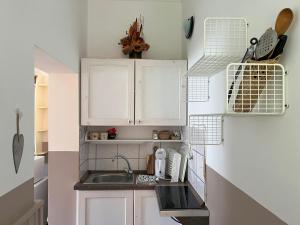 a small kitchen with white cabinets and a sink at Cseresznyés Ház in Lipót