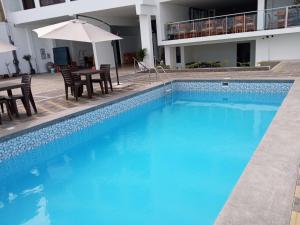 a large swimming pool with chairs and an umbrella at Hotel Huankarute in Huanchaco