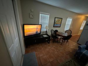 un salon avec une télévision et une table avec des chaises dans l'établissement Key West Style Historic Home in Coconut Grove Florida, The Blue House, à Miami