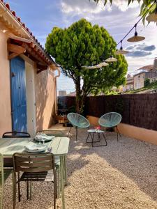 a patio with tables and chairs and a tree at La maison des cerisiers in Bédoin