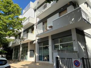 un edificio blanco con grandes ventanas y un árbol en Appartamento Stella marina, en Pesaro