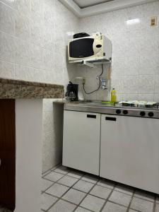 ヴィラ・ヴェーリャにあるFlat com vista da Praia da Costa 111の白いキャビネットと壁掛けテレビ付きのキッチン