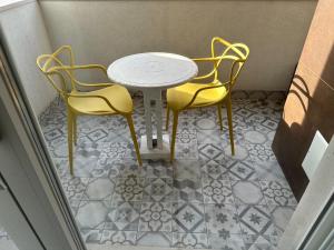 two yellow chairs and a table on a tiled floor at Casa MarFe in Grottaglie