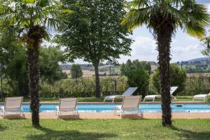 a group of chairs and palm trees next to a swimming pool at Assisi Villa Simi in Petrignano