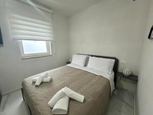 a white bedroom with a bed with towels on it at Casa MarFe in Grottaglie