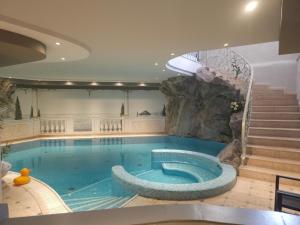 a large swimming pool in a building with a rock wall at Hotel Tonnerhof in Racines