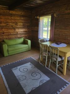 a living room with a table and a green couch at Šimtametis namelis in Anykščiai