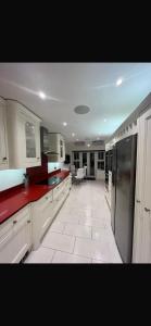 a large kitchen with white cabinets and red counter tops at Bramble Close in Chalfont Saint Peter