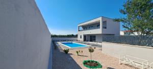 a house with a swimming pool next to a fence at Villa Mare Pirovac in Pirovac