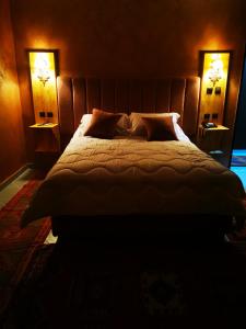 a bedroom with a large bed with two lamps at Hotel Saghro in Tinerhir