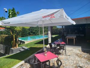 Ein weißer Sonnenschirm über zwei Tischen und einem Pool in der Unterkunft A Quinta do Presidente 