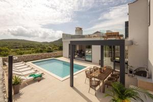 a house with a swimming pool and a table and chairs at Villa La Miel in Donji Majkovi