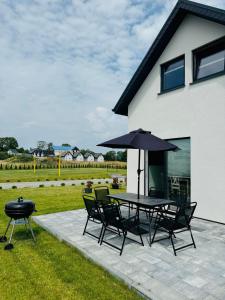 a patio with a table and chairs and an umbrella at Domki Letniskowe Vitamin Sea in Sarbinowo