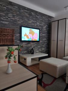 a living room with a tv on a brick wall at CityCenter - Cozy, tiny house in the city center in Subotica