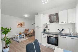 a kitchen with white cabinets and a living room at Blu infinito Apartment&studios in Rovinj