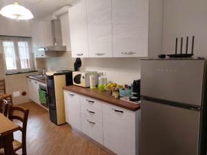 a kitchen with white cabinets and a stainless steel refrigerator at Casa Nonna Maria - Val Fontanabuona in Aveggio