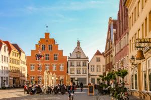 a group of people riding bikes down a street with buildings at Tohuus1875 in Warendorf