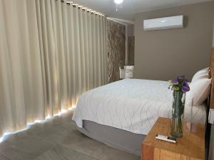 a bedroom with a bed and a vase of flowers on a table at AVE SUITES CAMPESTRES Jalpan de Serra in Cunas