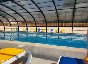 a large swimming pool with chairs in a building at Chalet Domaine de Marcilly in Marcilly-sur-Eure