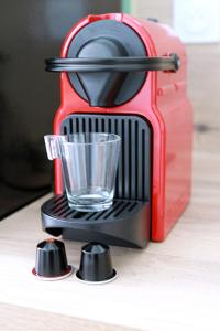 a red coffee maker with a glass on a table at Appartement Terrasse et Jardin in Périgueux
