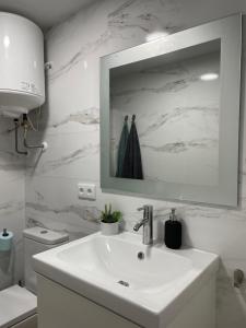 een witte badkamer met een wastafel en een spiegel bij Apartamento Granadella in Platja de l'Arenal