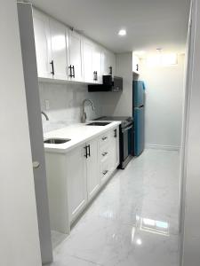 a white kitchen with a sink and a refrigerator at Contemporary Private Basement Suite in Markham