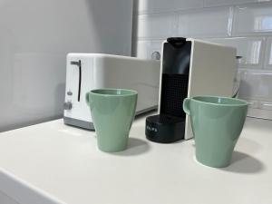 een witte magnetron en twee groene kopjes op een aanrecht bij Apartamento Granadella in Platja de l'Arenal