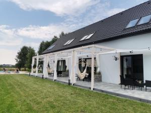 a white house with a porch with hammocks at 4 Pory Roku in Darłowo