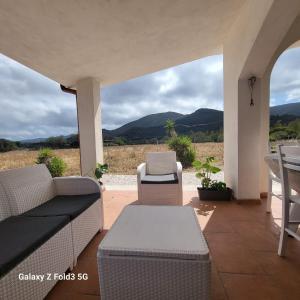 un patio con sofá, sillas y montañas en Elisabeth's House, en Villaputzu