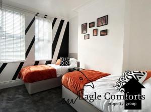 a bedroom with two beds and an orange blanket at 5 Bedroom House-20 percent off monthly stays in Neepsend +2 photos