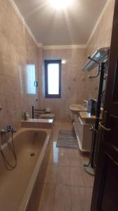 a large bathroom with a tub and two sinks and a window at La casa sul mare in Patti