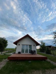 una piccola casa bianca con un ponte nell'erba di Zielony Zakątek a Stary Bubel