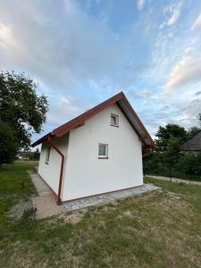 un edificio bianco con il tetto rosso su un campo di Zielony Zakątek a Stary Bubel