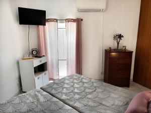 a bedroom with a bed and a dresser and a television at Casinha das Bonecas in Monchique