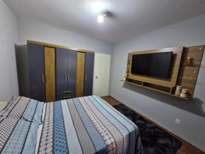 a bedroom with a bed and a flat screen tv at Apto no Centro de São Leopoldo in São Leopoldo