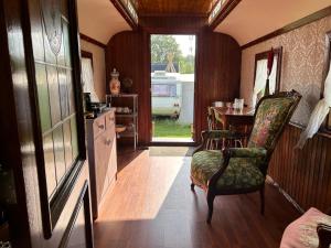 a room with a table and a chair and a kitchen at Pipowagen in Sleen