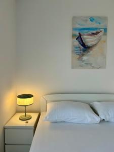 a bedroom with a bed with a lamp and a painting at Apartman Ante Škoda Pivica in Povljana