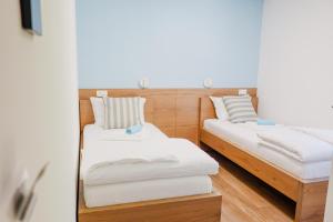 two beds in a room with white sheets at Villa Ali in Illidža