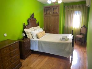 a green bedroom with a bed and a dresser at Casa Dina Doceira in Geres