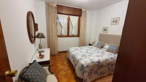 a bedroom with a bed and a mirror and a window at Tercero Loft Susana in San Vicente de la Barquera