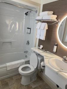 a bathroom with a toilet and a tub and a sink at Sunny Isle Motel in Summerside +26 photos